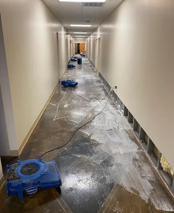 Air movers drying a water-damaged floor along a Dallas hallway